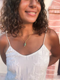 Gold chain necklace with coral and turquoise spiral shell pendant, close-up on model
