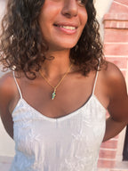 Gold chain necklace with coral and turquoise spiral shell pendant, close-up on model