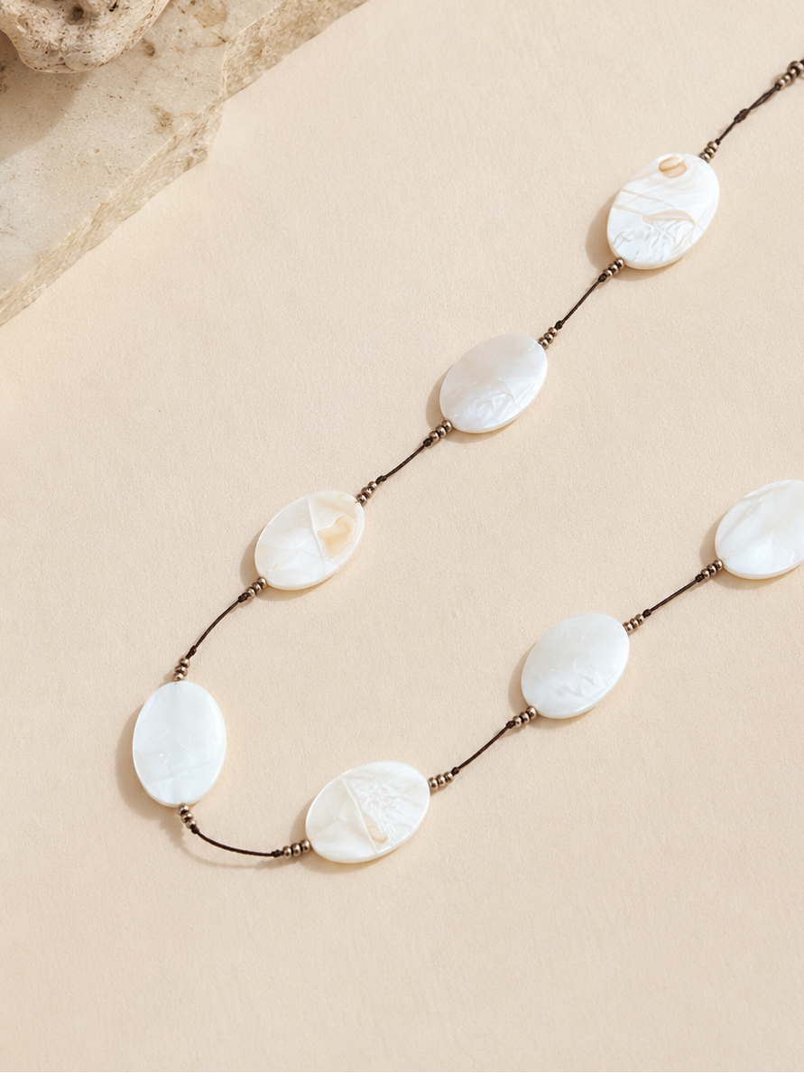 phone chain that consists of smooth marbled pearlescent beads spaced along a fine dark cord with tiny bronze spacer beads