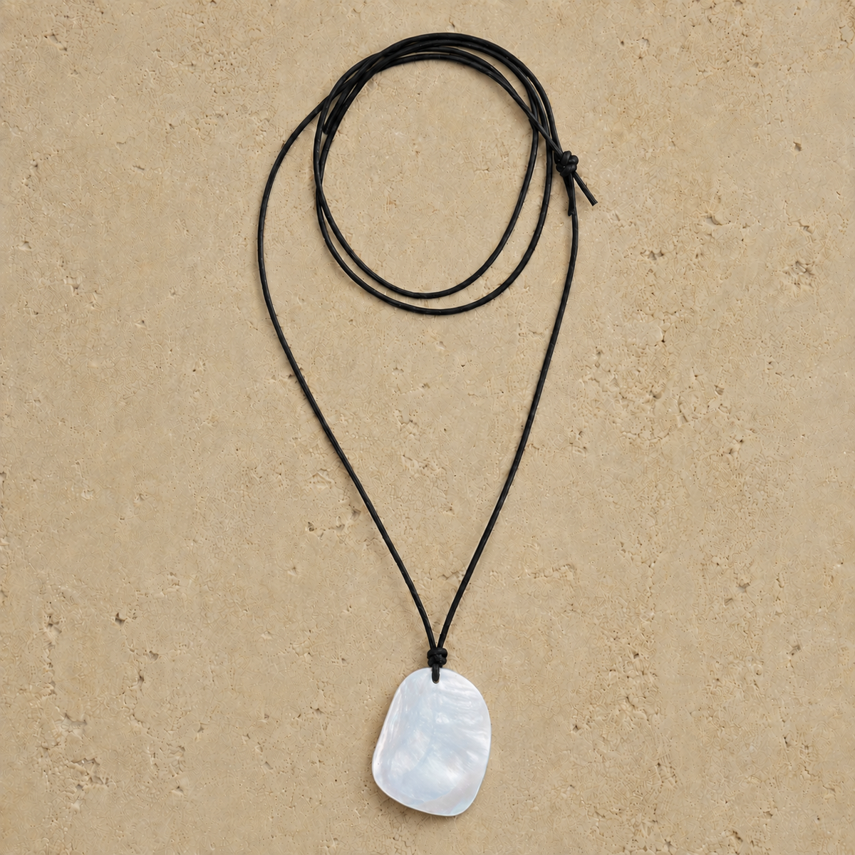 necklace with a white pearlescent pendant tied to a black wax cord 